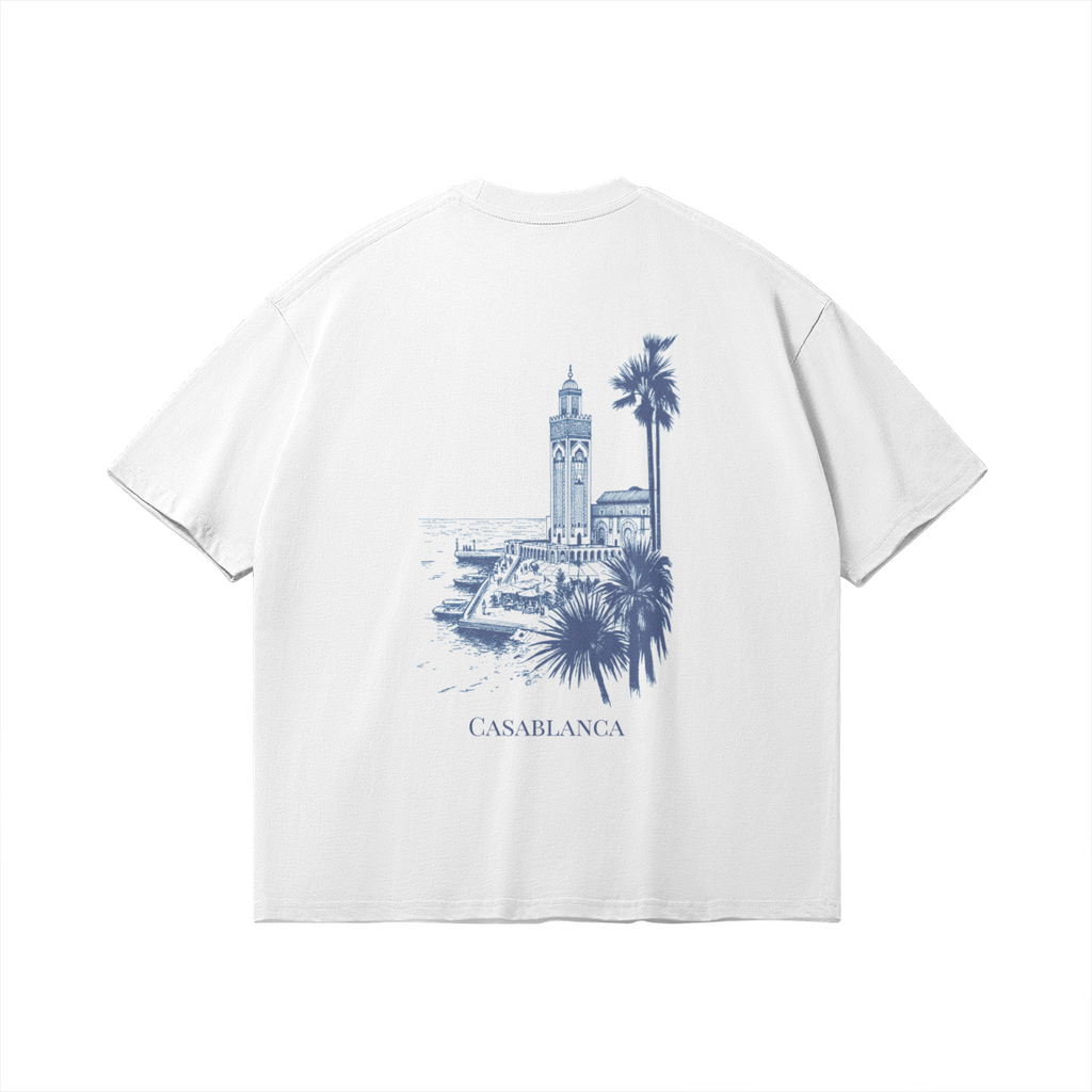 Back of white t-shirt featuring a detailed blue architectural sketch of the Hassan II Mosque and palm trees, minimalist luxury streetwear fit.