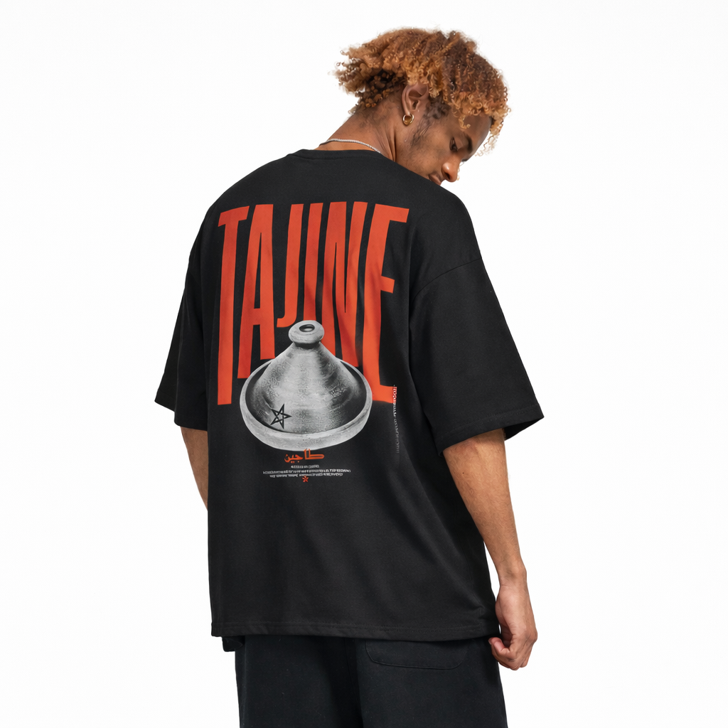 Back view of man wearing a Bold red and clay Tajine graphic on premium black t-shirt, minimalist Moroccan streetwear, heavyweight boxy fit and standing in plain background