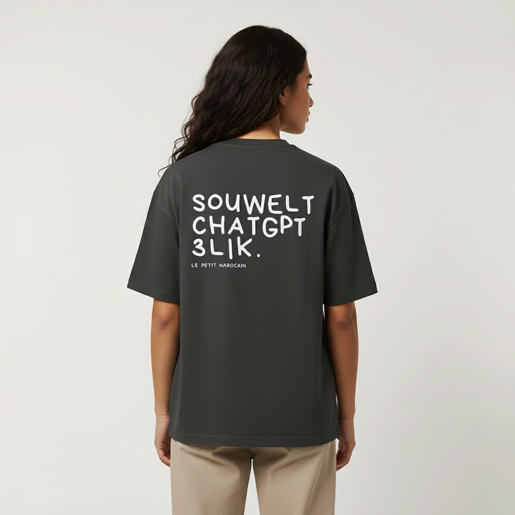 Woman wearing a black heavyweight t-shirt with high-contrast white hand-drawn text 'SOUWELT CHATGPT 3LIK', oversized streetwear silhouette against a plain background.