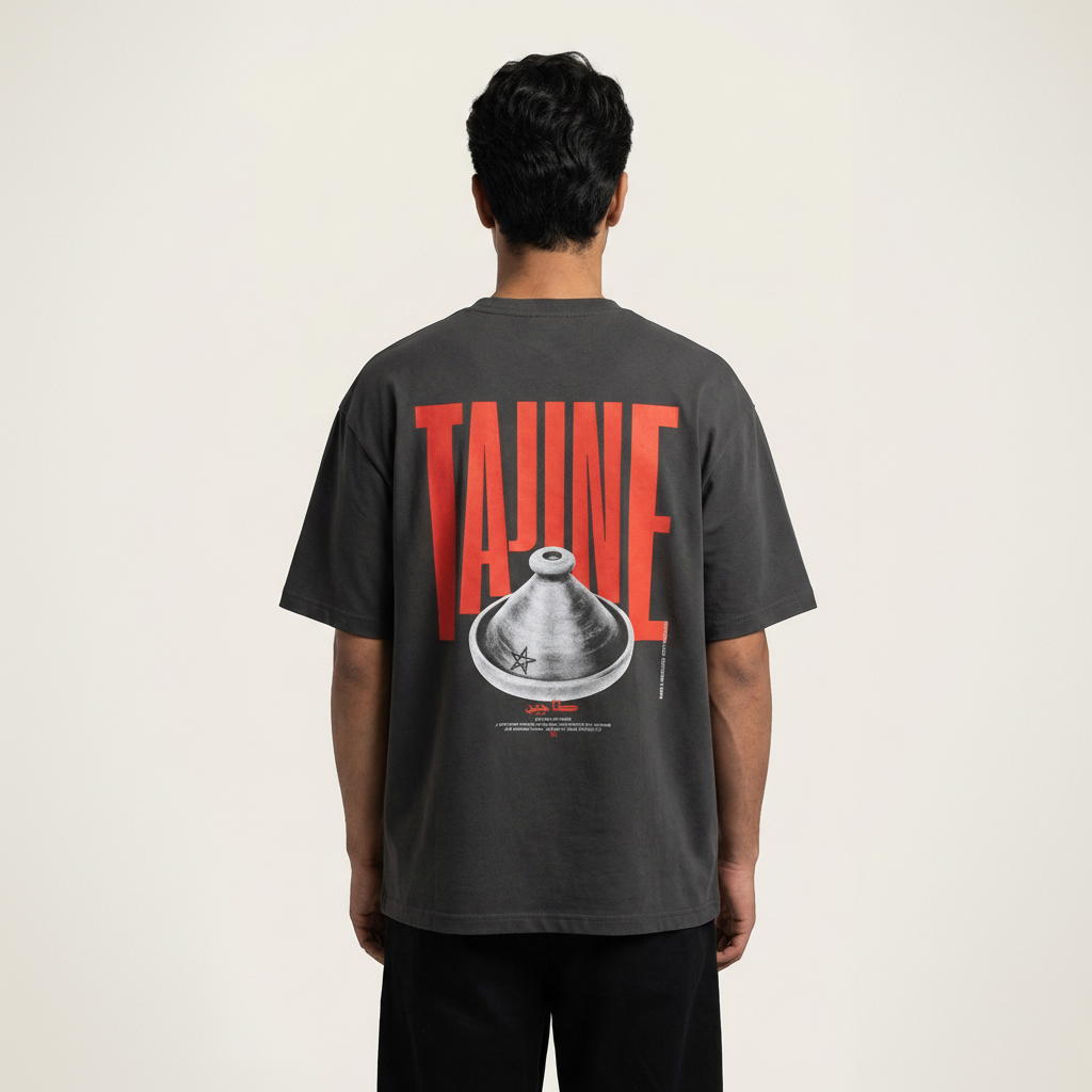 Back view of man wearing a Bold red and clay Tajine graphic on premium black t-shirt, minimalist Moroccan streetwear, heavyweight boxy fit and standing in plain background straight.